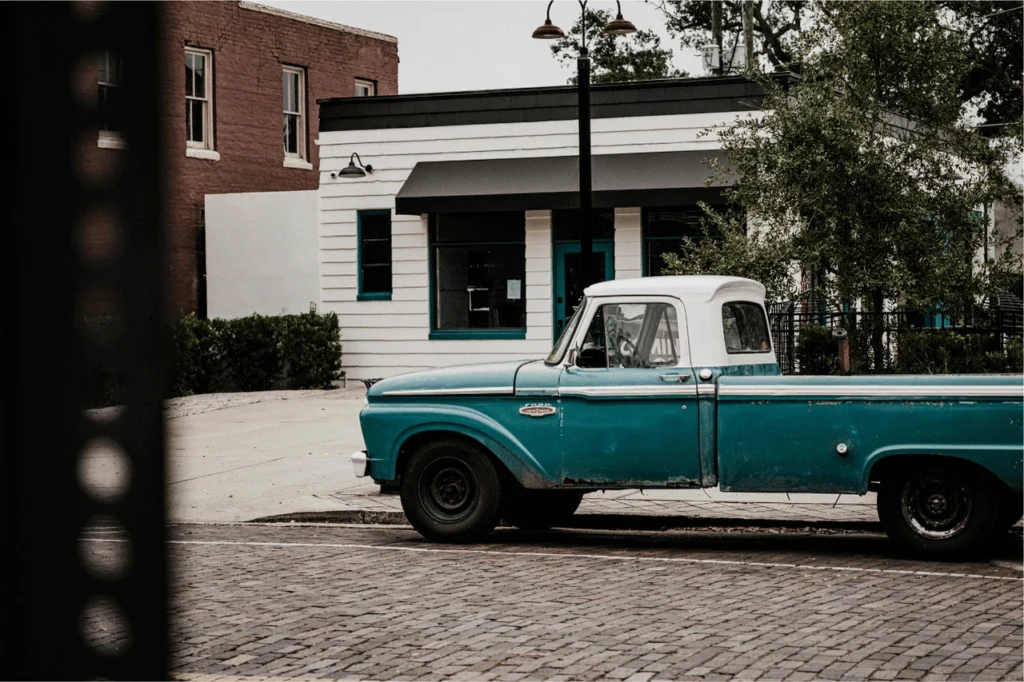 Old blue ford truck parked next to white building