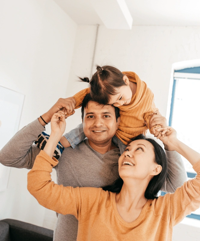 Father and mother placing daughter on fathers shoulders